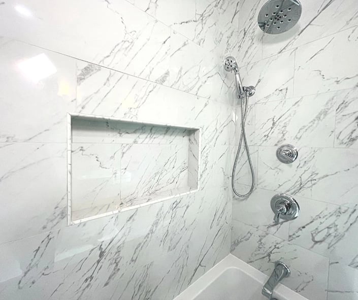 A shower niche was created using porcelain tile that looks identical to marble.
