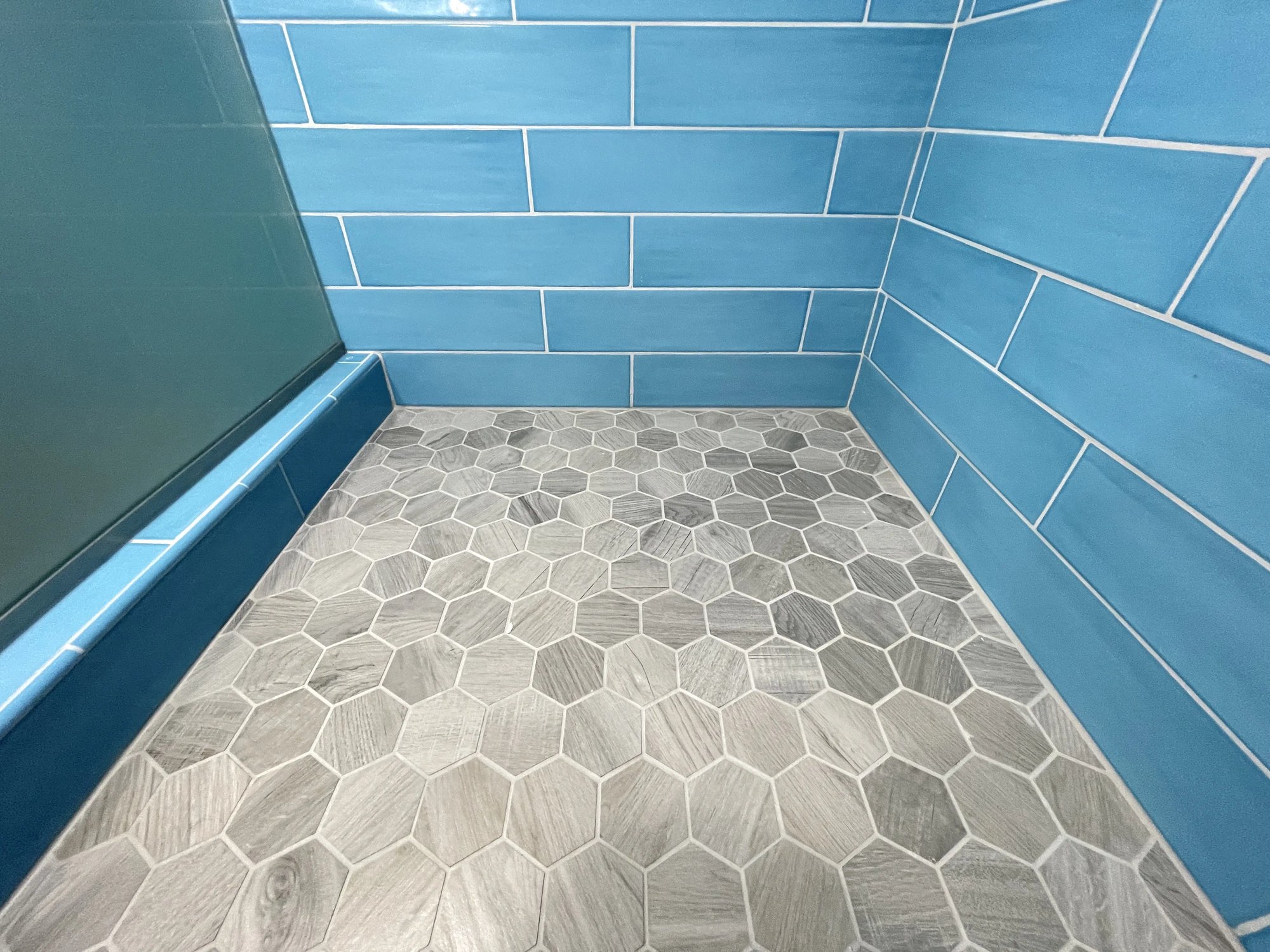 Gray carrara hex tile was used for the shower floor of this master bathroom remodel.